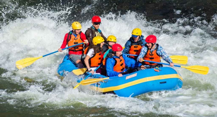 a group of gap year students paddle a raft through whitewater on an outward bound semester expedition 
